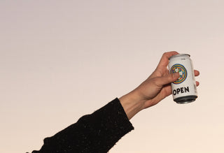 OPEN_Beer_Tino's Hand_Holding_Beer_in_the_pink_sky_finger_on_Logo__OPEN_Brewing